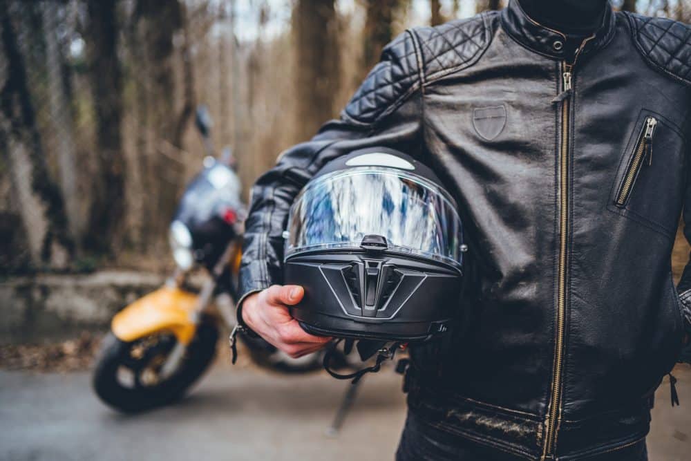 A motorcyclist holding his helmet.