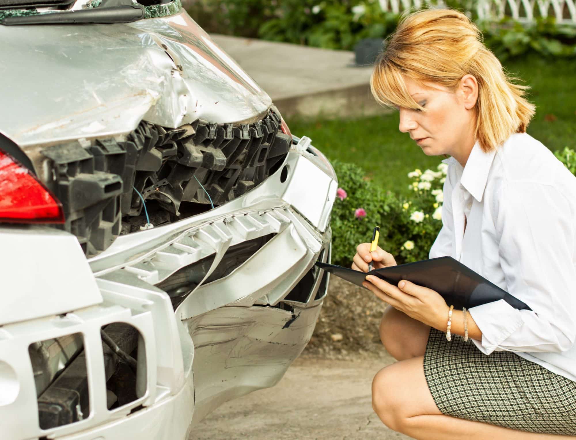 insurance adjuster inspecting car accident damage