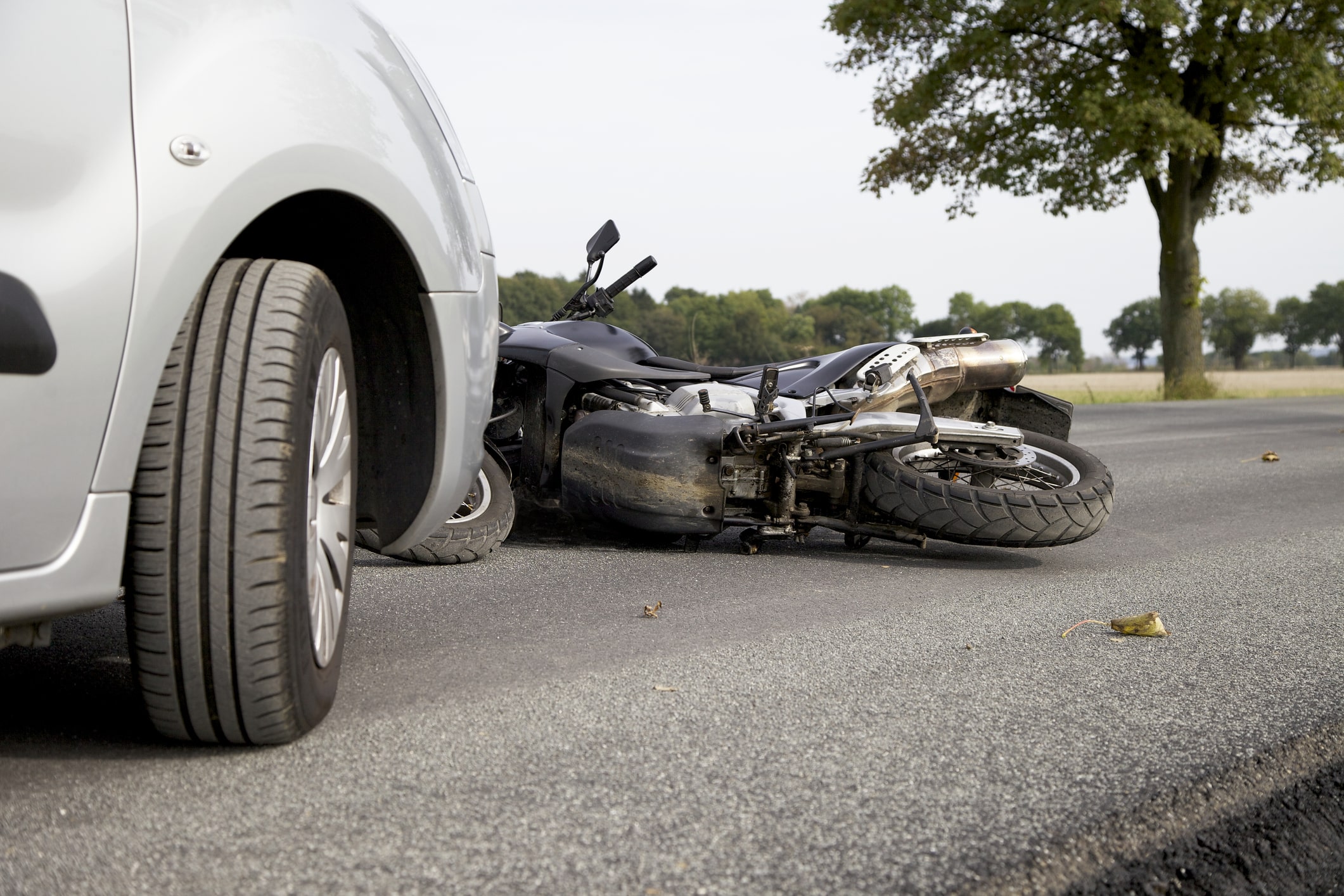 The aftermath of a Millbrook motorcycle accident is seen, with a bike lying down in the road next to the car that hit it.
