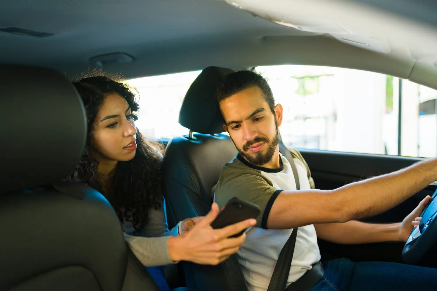 A Millbrook rideshare driver looks at the passenger’s phone as she shows him directions to her destination.