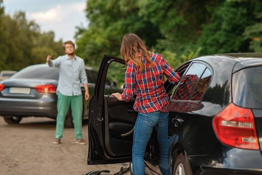 Drivers who have been in a minor car accident are seen talking to each other from outside of their vehicles.