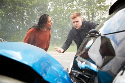 Drivers who have been in a crash appear to be arguing next to their wrecked vehicles.