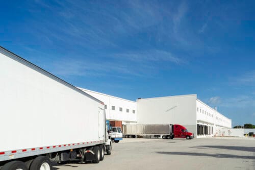 Large trucks at the loading dock of a warehouse.