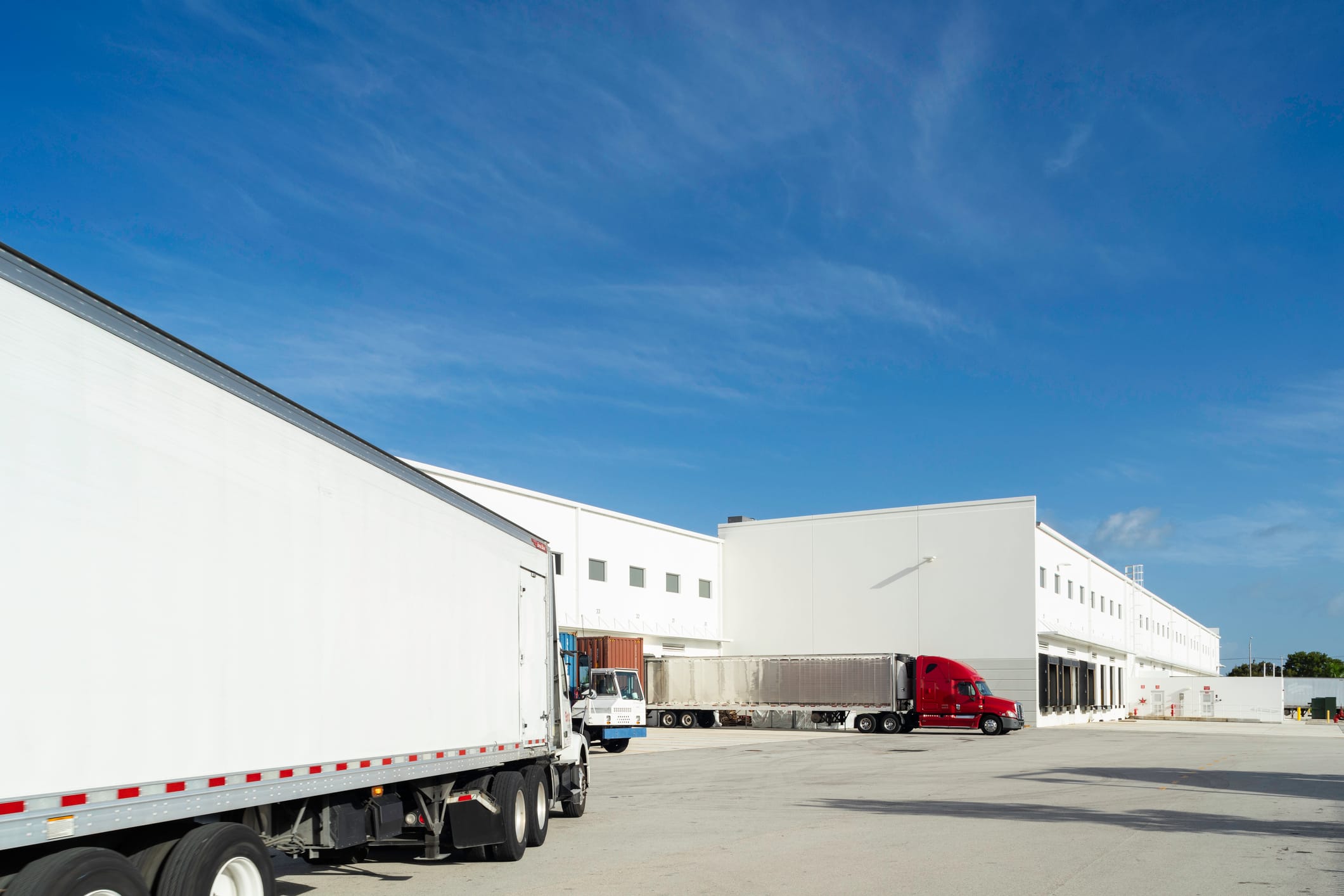 Large trucks at the loading dock of a warehouse.