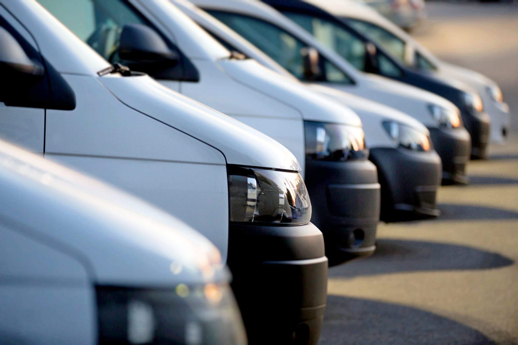 A row of white and black commercial vehicles (delivery vans).