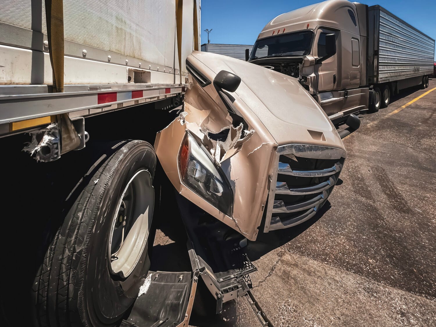 A tan semi truck crashed into the rear of a tractor-trailer on the highway.