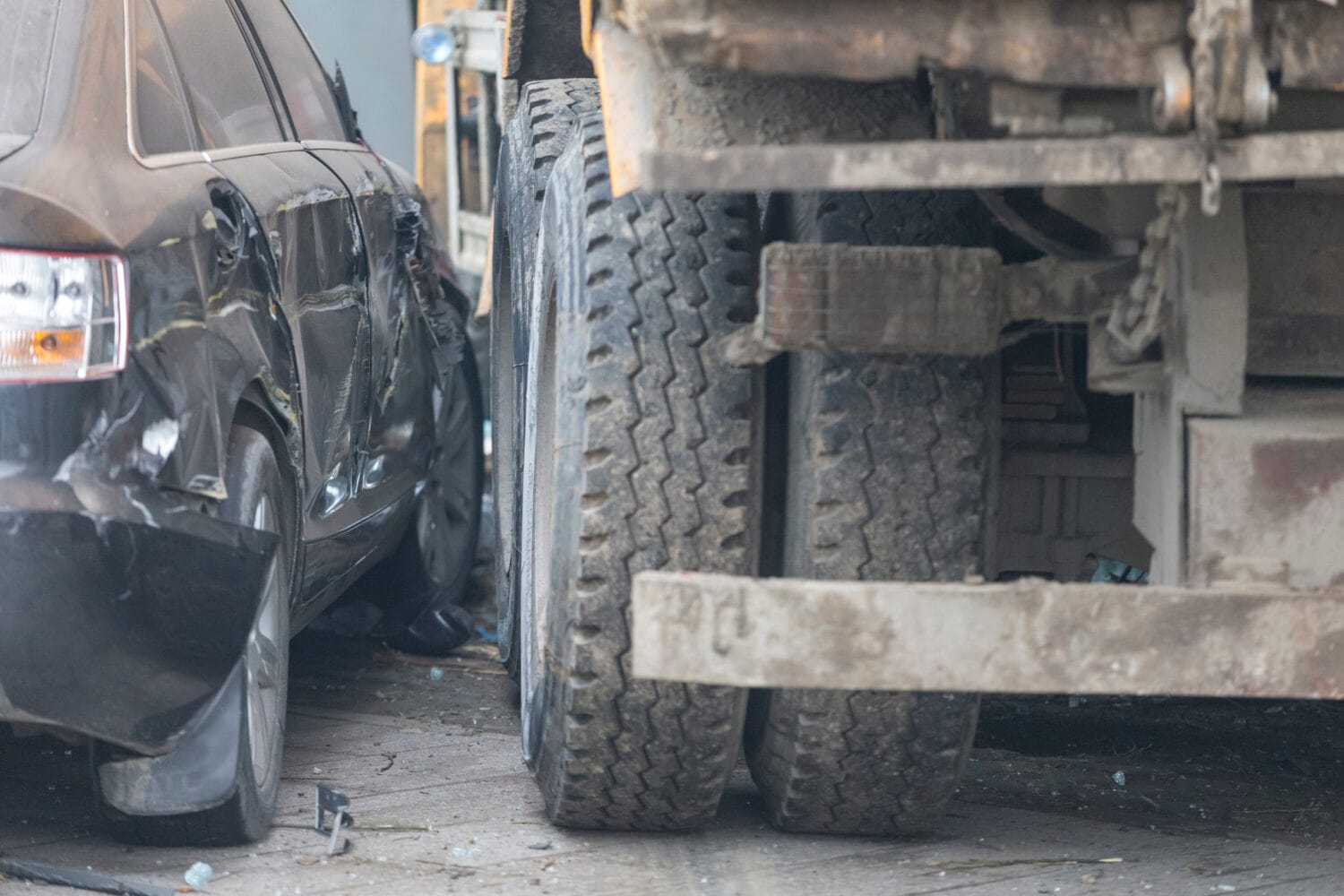 A damaged car is parked next to a large truck after an accident.