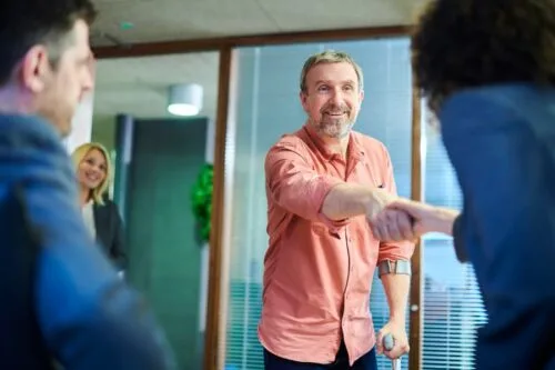 Car accident claimant using cane smiles during meeting with legal team.