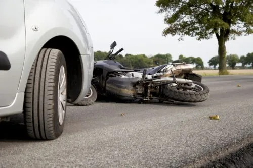 Closeup of car stopped in front of motorcycle accident on rural Alabama road.